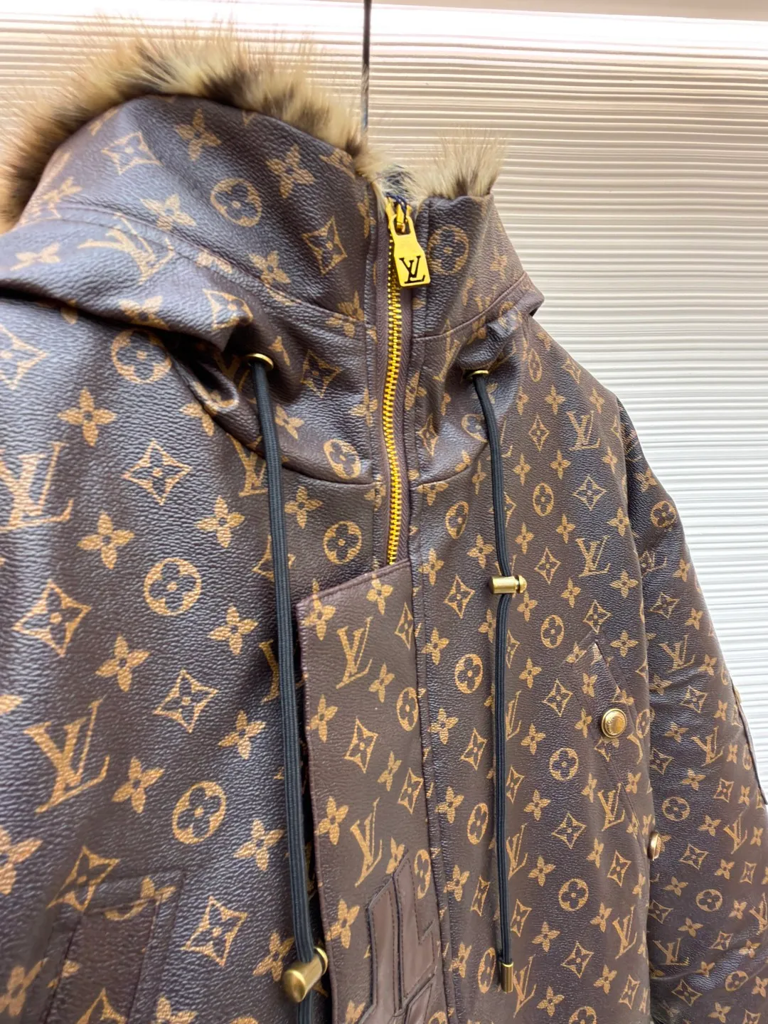 LOUIS VUITTON letter print hooded jacket ●Original version: Purchased and developed for 69999 ●Item number: 1681985-E40 ●Fabric: cotton fabric ●Technology: printing production ●Color: brown ●Version: fitted version ●Weight: about 1810 grams ●Size: 46-48-50-52 ●Description: This printed jacket is made of embossed leather fabric with a dark brown base and is fully printed with the classic Monogram pattern. The embossing process gives the logo a three-dimensional texture. The edge of the hood is spliced ​​with a natural fur collar, and the brim is equipped with an adjustable drawstring (metal rope buckle) to enhance warmth and style. The placket is double-closed with a two-way metal zipper and brass snap buttons. The zipper puller and snap button are both engraved with the brand logo, which is thick and durable. The body is designed with multiple pockets, and the pockets are edged with the same material + metal snap buttons for reinforcement. The left sleeve is equipped with a hidden adjustment tab. The interior is filled with high-fill down cotton, and the stitching adopts diamond-shaped quilting technology to prevent the filling from shifting. The seams are edged with leather of the same color, and the overall wiring is precise, taking into account warmth retention and luxurious texture. The overall wiring is straight and delicate, the fabric is comfortable and soft, and the color is consistent without color difference. It can be matched with the same style to create a fashionable look and control various occasions. Customized accessories, complete with three standards, same style for men and women!